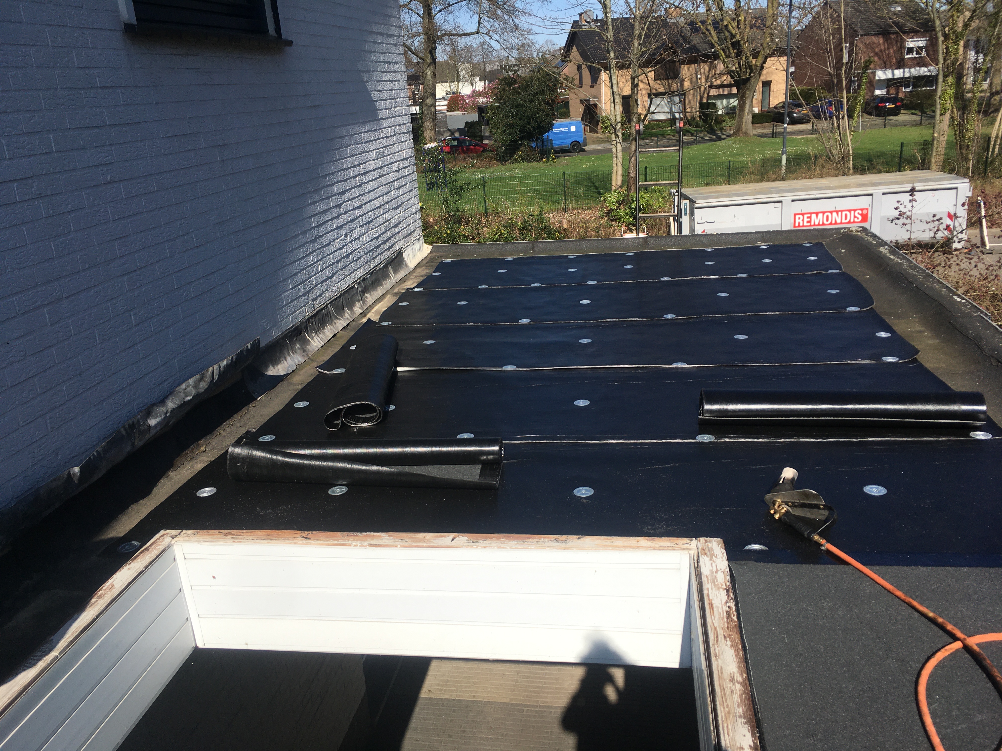 Tijdens: de oude bitumen dakbedekking is gereinigd, de lichtkoepel is verwijderd en de onderlaag wordt gemonteerd.
